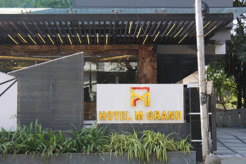 Hotel M Grand signboard beside the covered entrance and planter