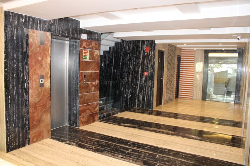 Lift lobby with black and copper marble walls and a wooden floor