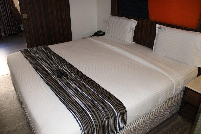 Double bed with a striped runner, pillows and bedside phone