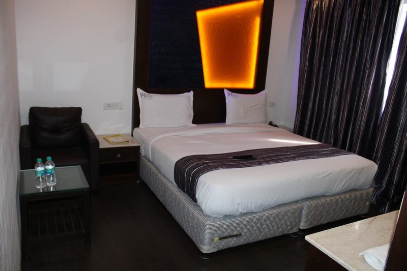 Double bed with an armchair, side table and backlit headboard panel