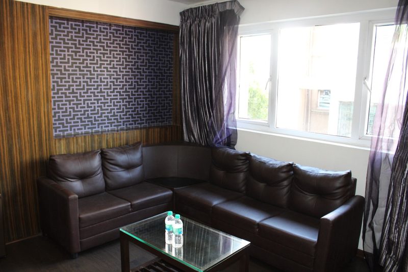 Corner leather sofa with a glass coffee table beside a window
